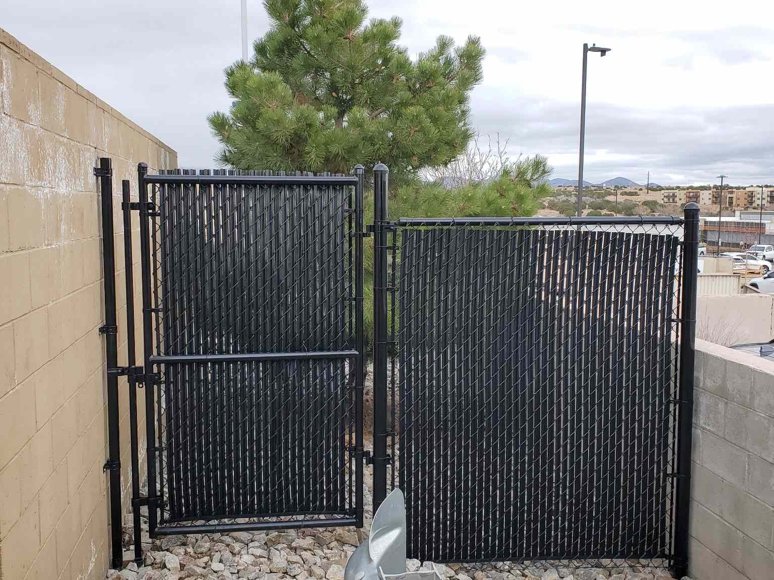 Black metal fence surrounding a yard with a tree