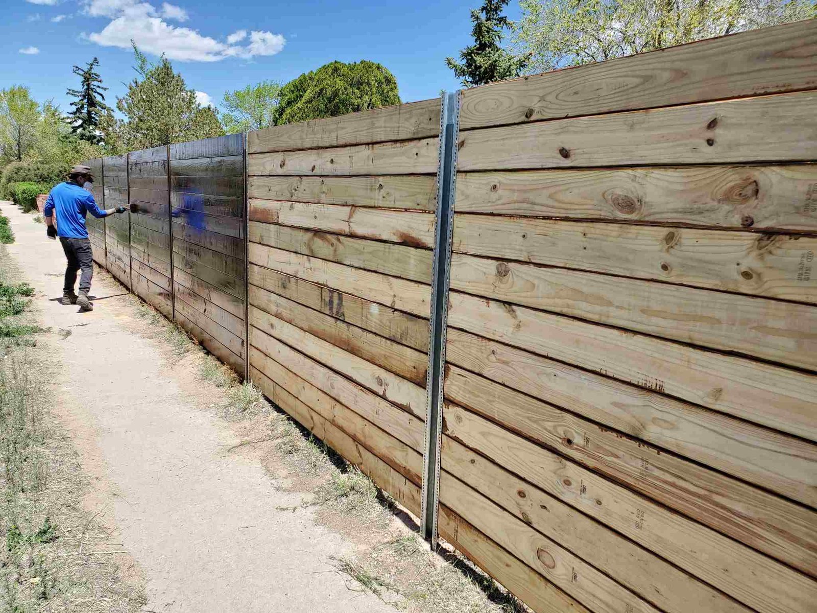 Crew member painting a wooden fence