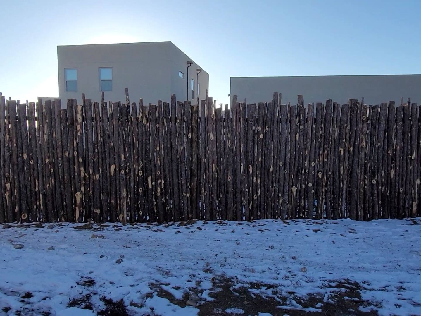 Wooden fence surrounding a house in a snowy landscape
