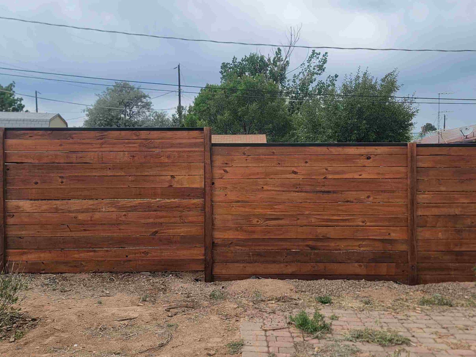 Wooden fence surrounding a yard with a house in the background