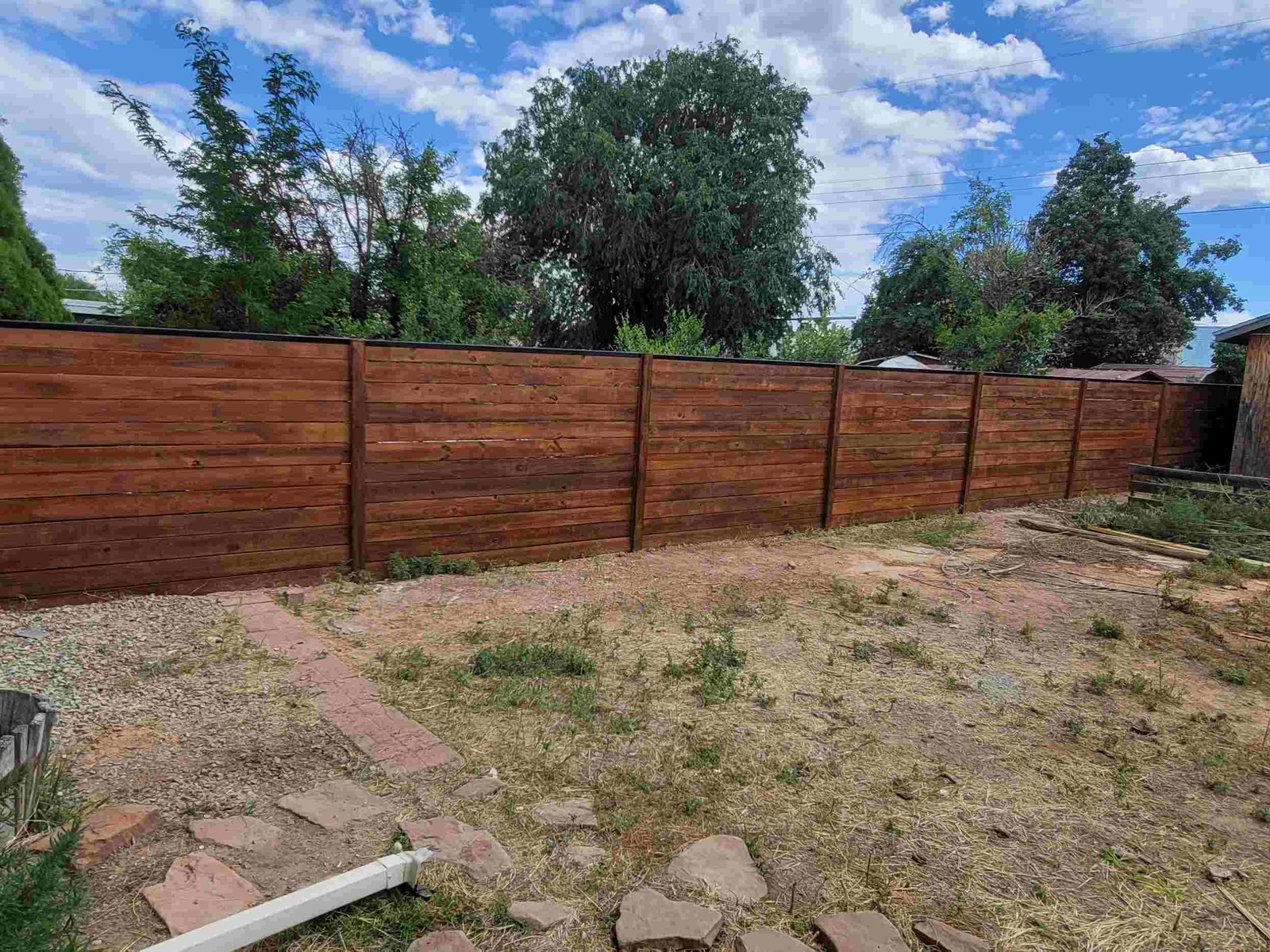 Backyard enclosed with a new wooden fence